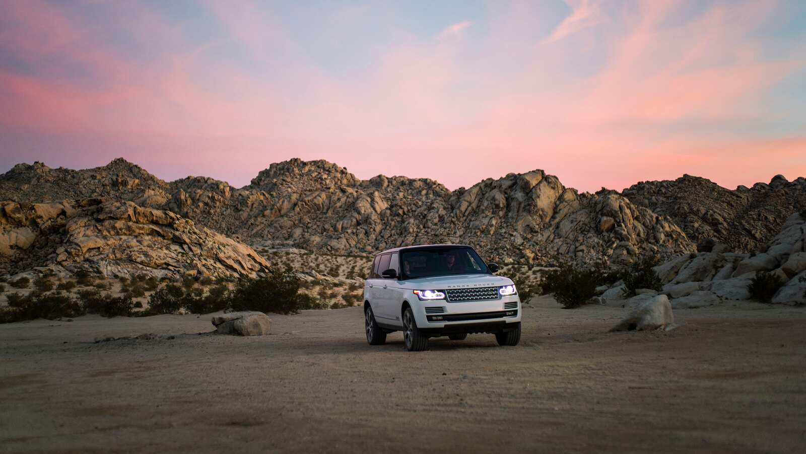 White Range Rover with boulders behind